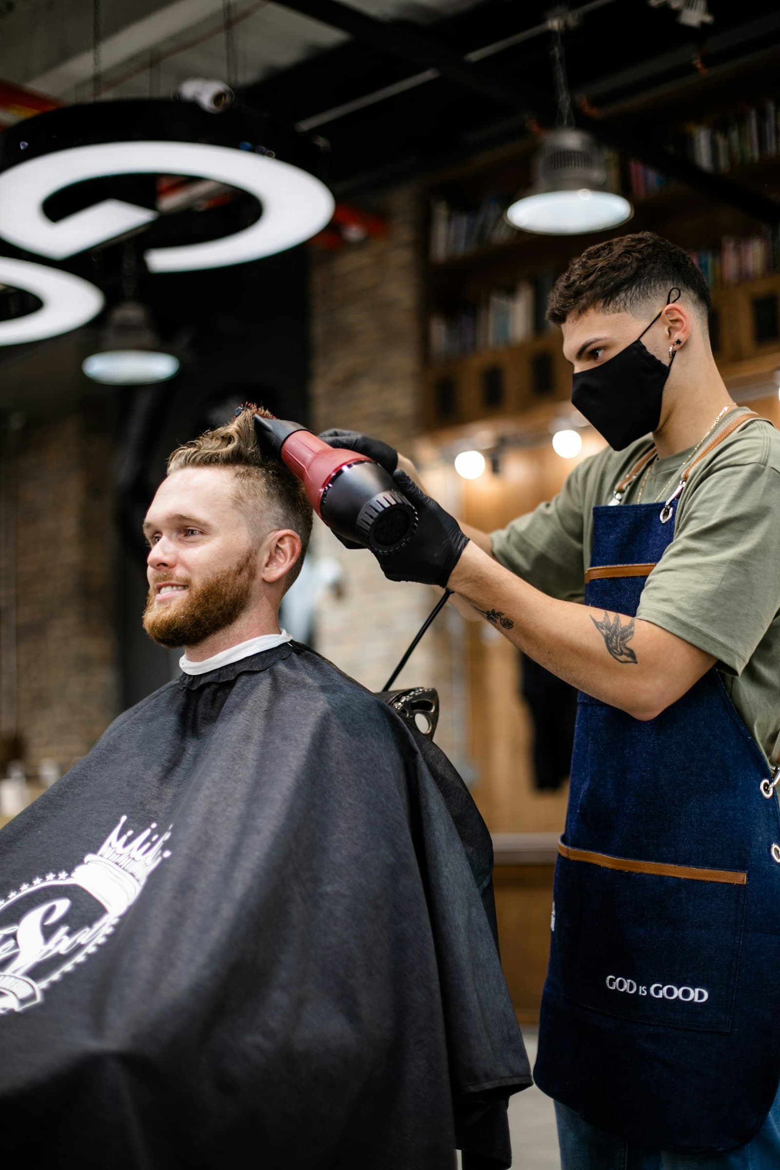Barbeiro a secar o cabelo de um cliente na loja