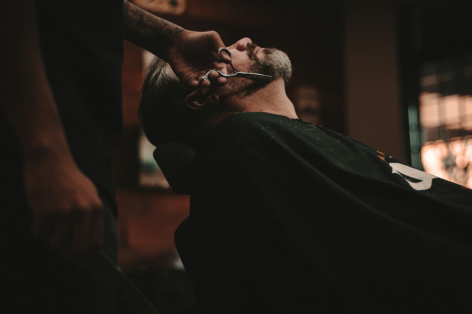 Cliente reclinado numa cadeira de barbeiro durante um corte de barba