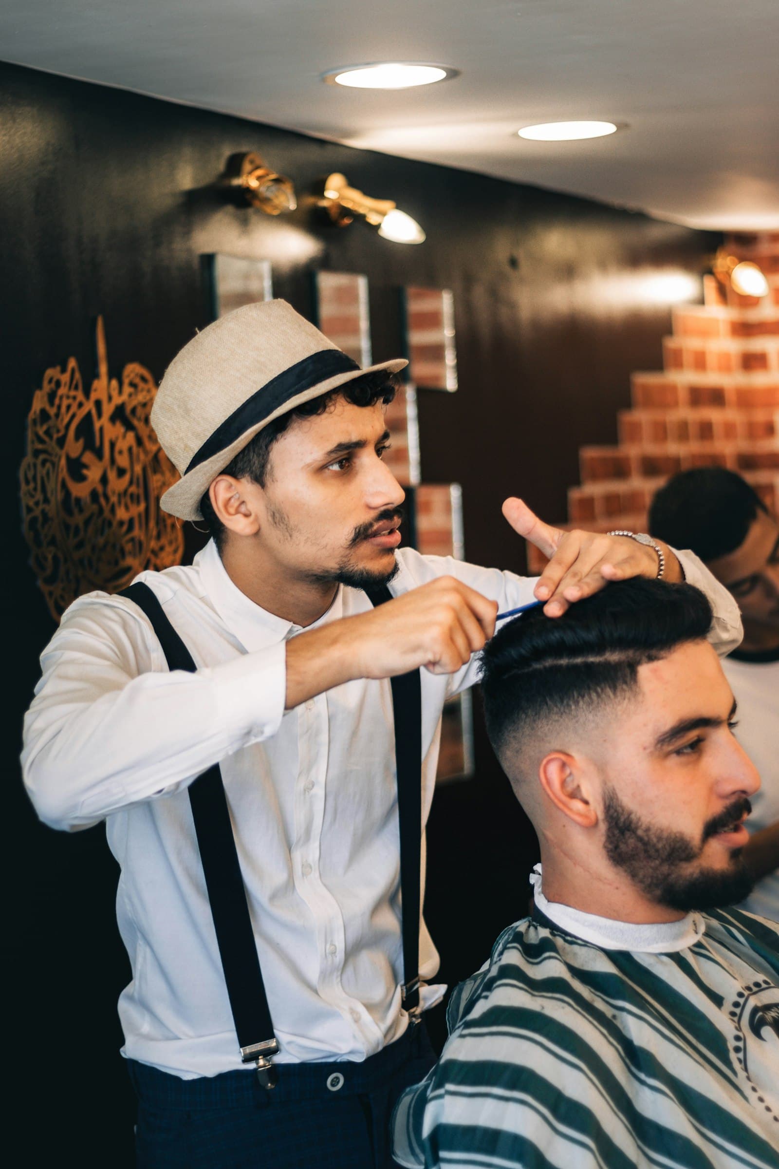 Barbeiro a pentear o cabelo de um cliente numa barbearia