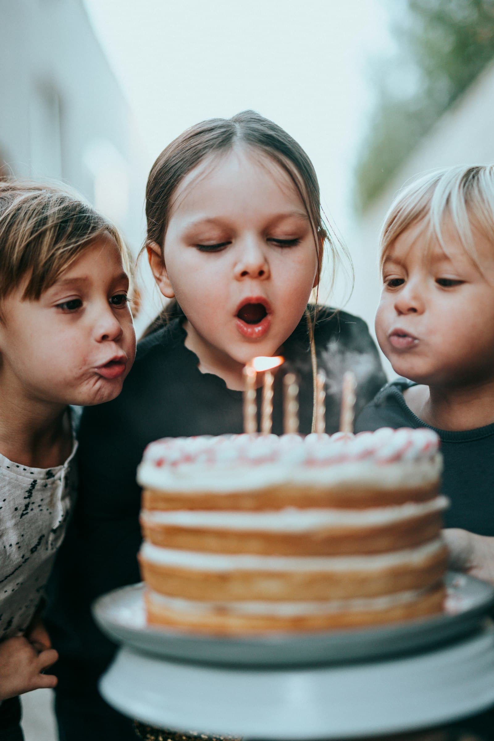 Crianças a soprar as velas de um bolo de aniversário