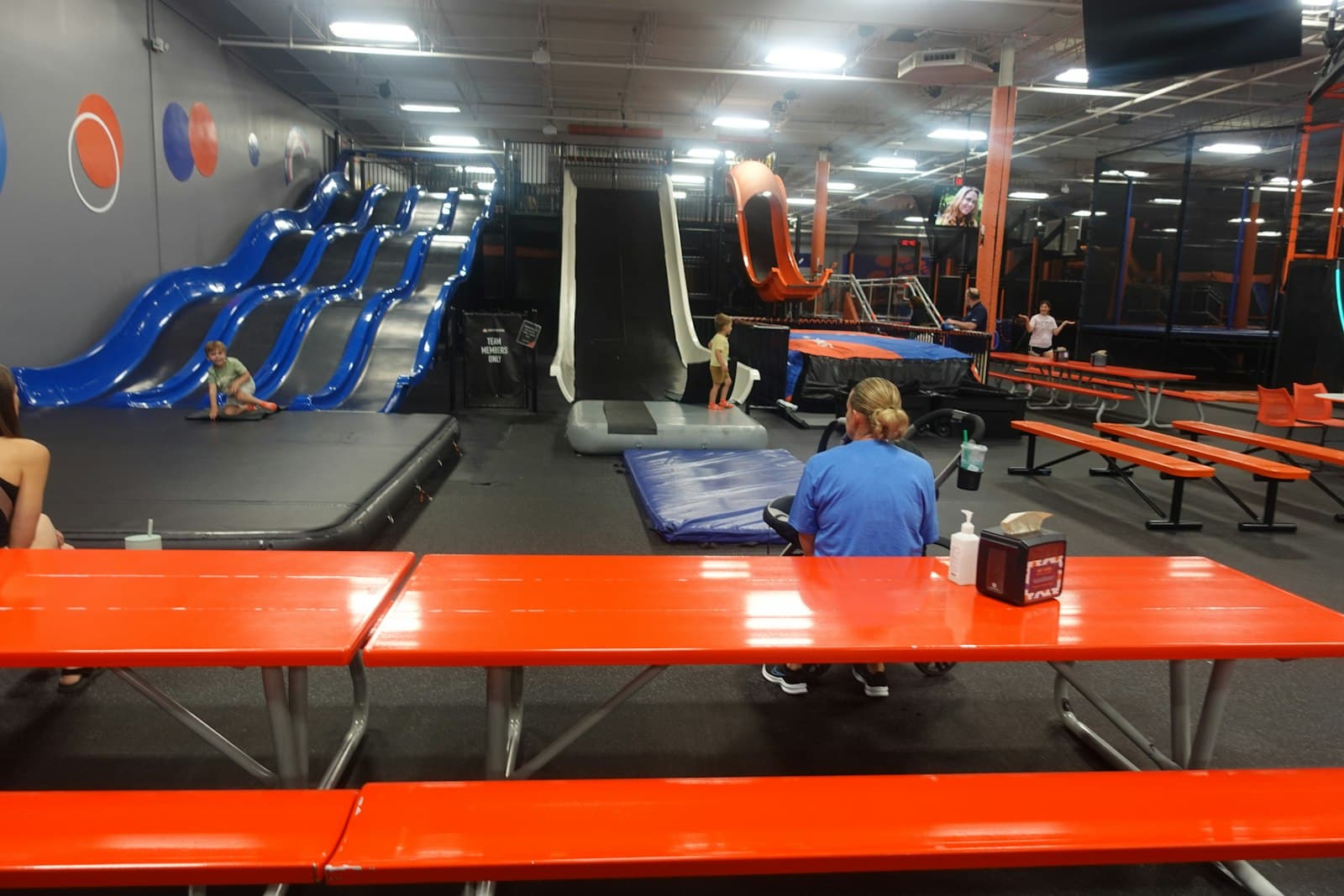 Parque indoor com trampolins, escorregas e mesas de apoio